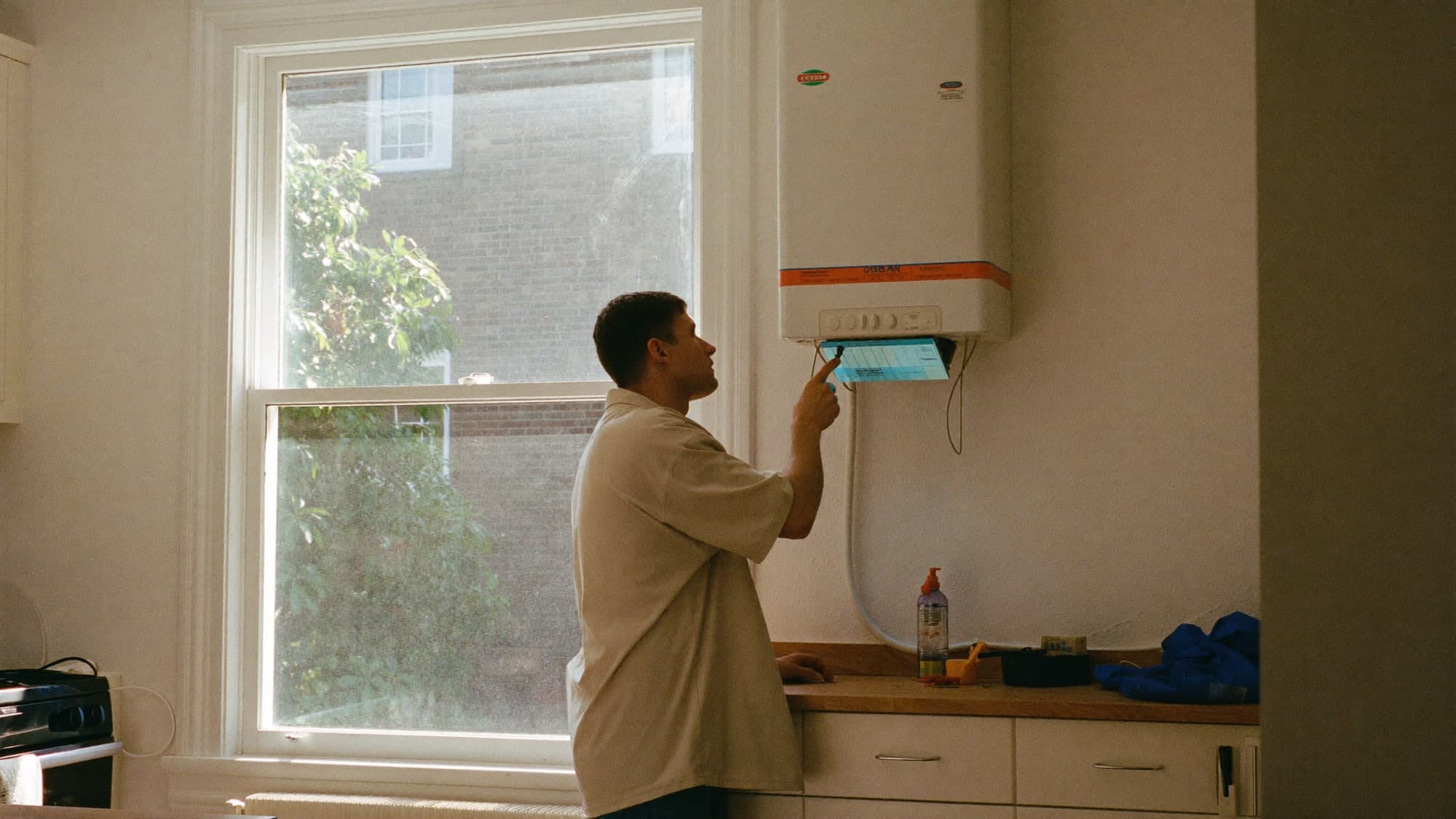 An engineer servicing a domestic boiler in a kitchen.