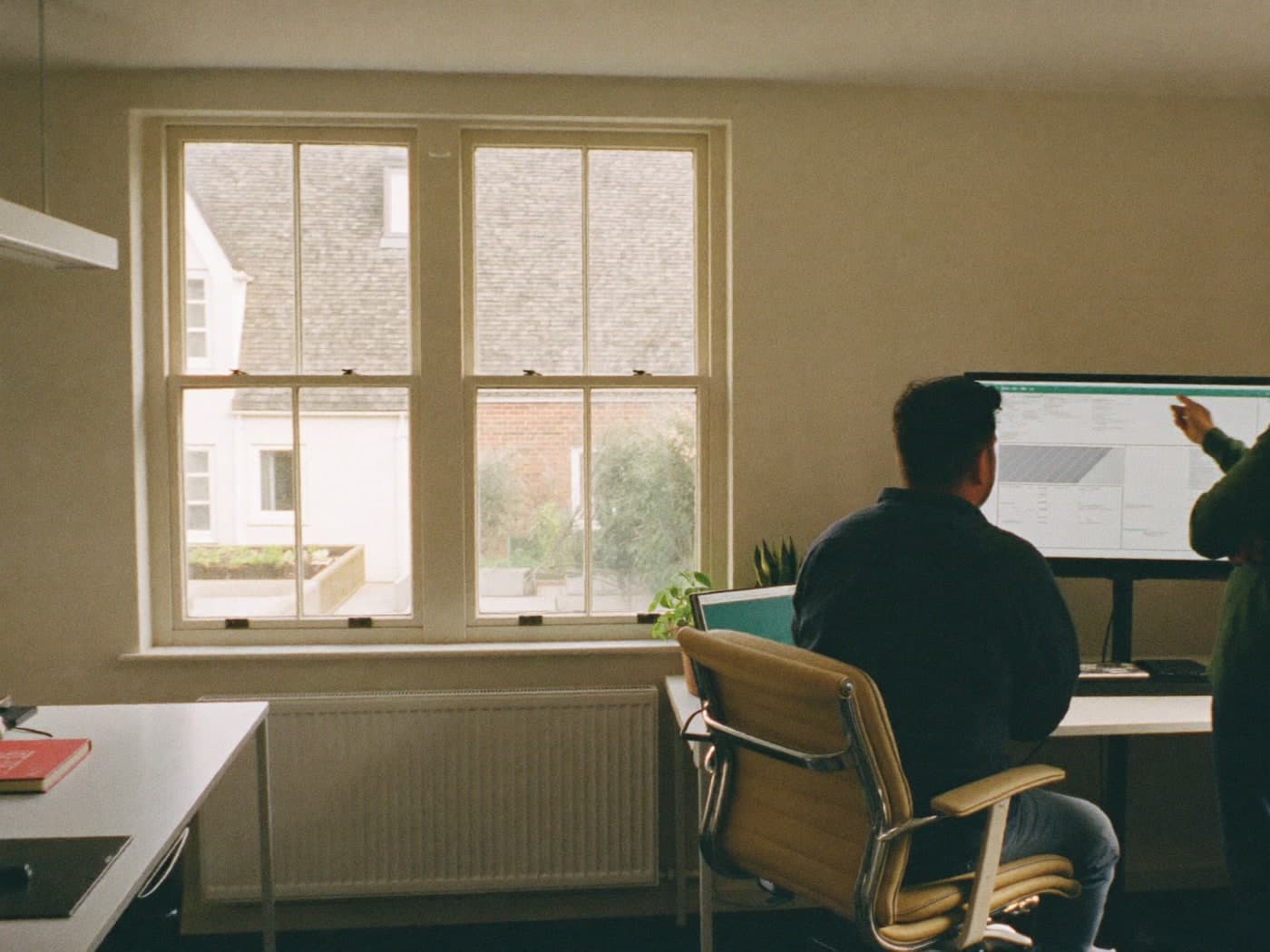 Two colleagues reading a report together at a screen.